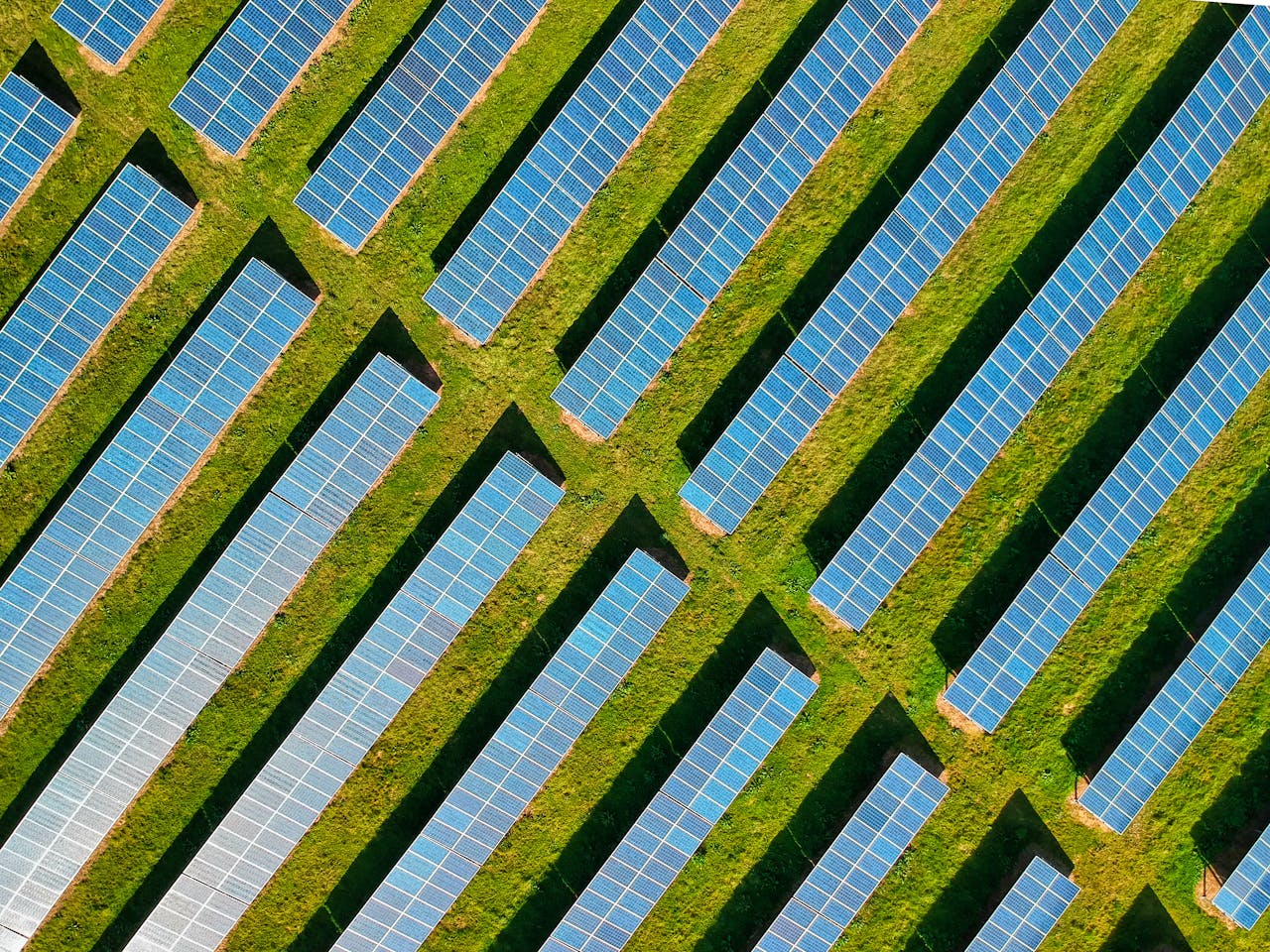 High-angle aerial shot of solar panels in a lush green field, located in Rockbeare, UK.