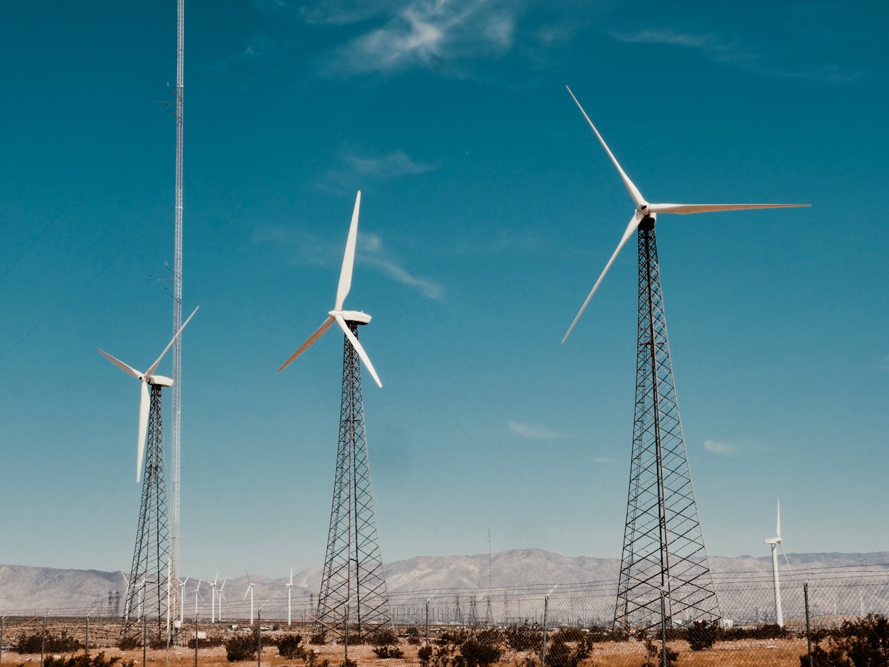 A wind farm with turbines against a clear blue sky in a desert setting.